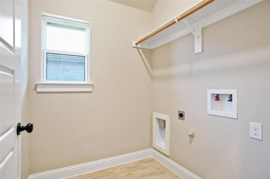 Clothes washing area with washer hookup, hookup for an electric dryer, hookup for a gas dryer, and wood-type flooring