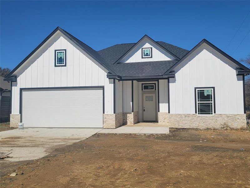 Modern inspired farmhouse featuring board and batten siding, driveway, a garage, a shingled roof, and covered porch