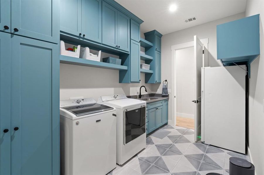 Washroom with sink, washing machine and clothes dryer, light tile flooring, and cabinets