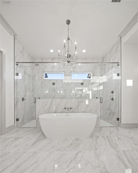 Full bath featuring a freestanding tub, a marble finish shower, suspended lighting, and tile walls Full bath featuring a freestanding tub, a marble finish shower, suspended lighting, and tile walls