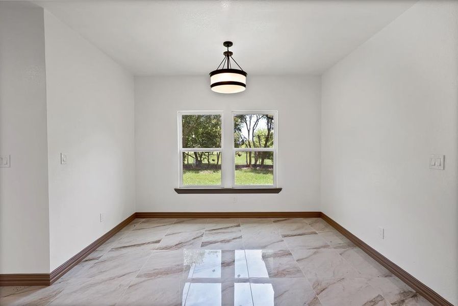 Spare room featuring baseboards and light marble finish floors