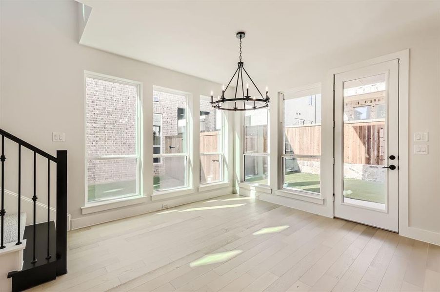 Unfurnished dining area with a chandelier, light hardwood / wood-style flooring, and a healthy amount of sunlight