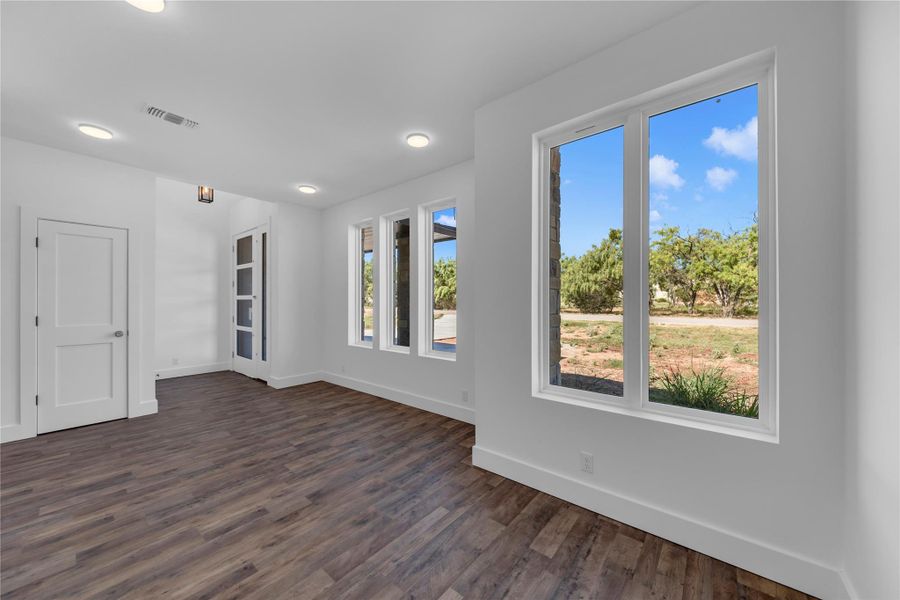 Front entry walking into the home.  Rich wood-look flooring and recessed lighting frame views of the surrounding natural landscape.