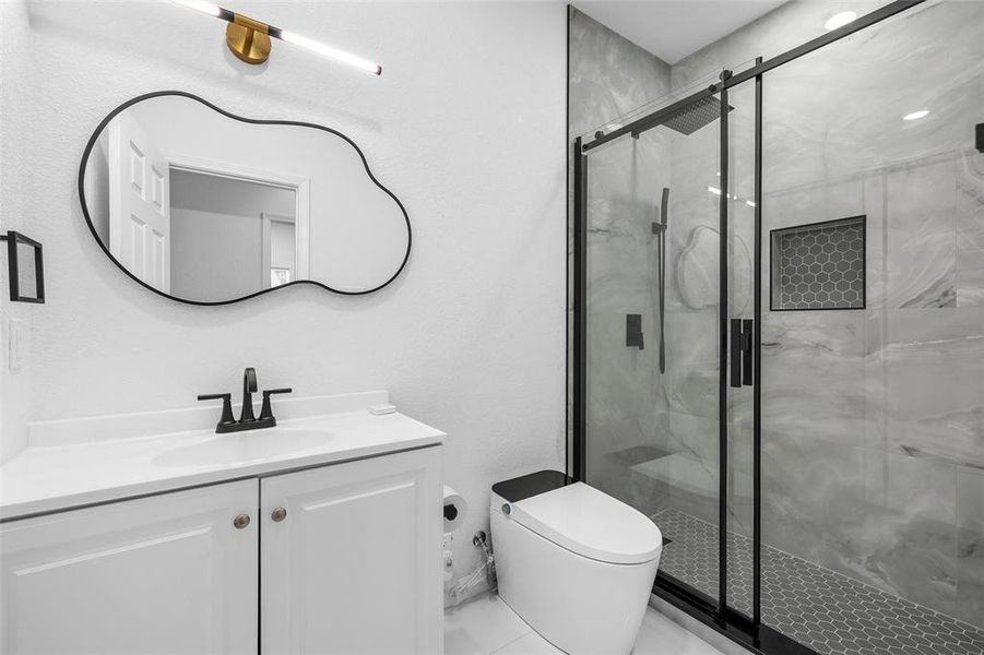 Contemporary bathroom featuring a white vanity with integrated sink, black faucet, and a decorative wall mirror Contemporary bathroom featuring a white vanity with integrated sink, black faucet, and a decorative wall mirror