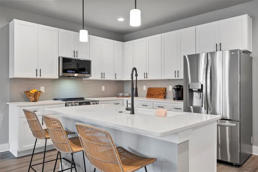 Kitchen featuring a kitchen island with sink, tasteful backsplash, and stainless steel appliances