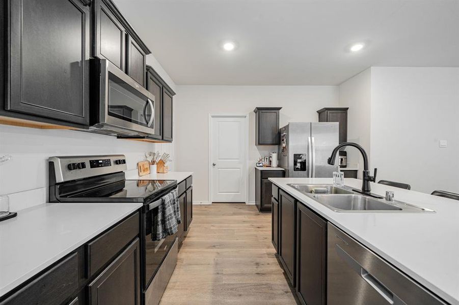 Kitchen featuring stainless steel appliances, light LVP flooring, recessed lighting, and light quartz countertops Kitchen featuring stainless steel appliances, light LVP flooring, recessed lighting, and light quartz countertops