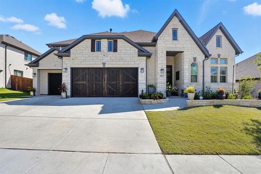French country home with driveway, brick siding, a garage, and stone siding