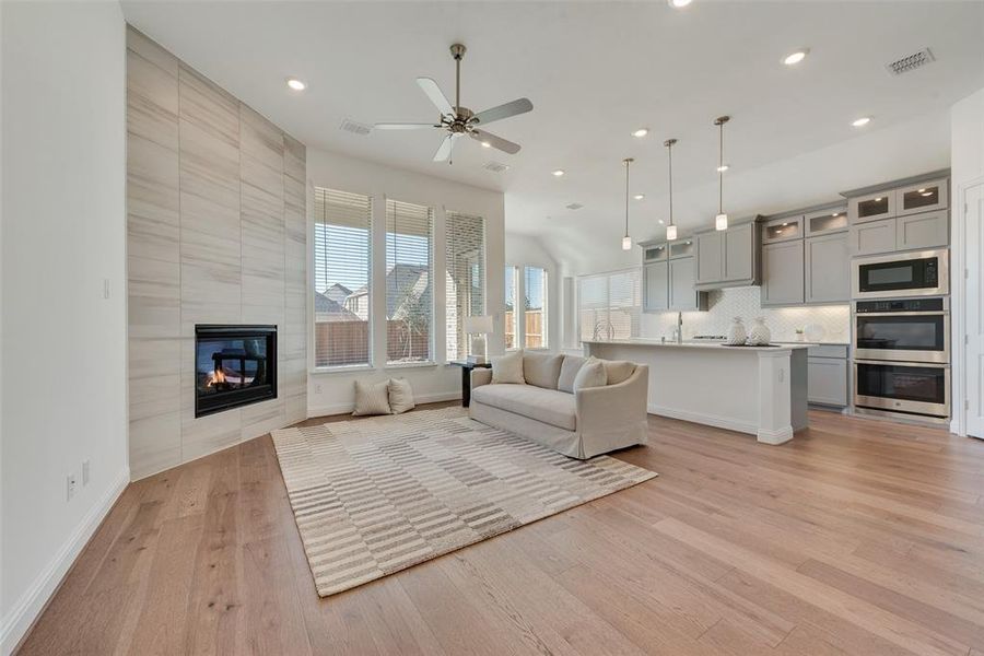 Unfurnished living room with a tile fireplace, light hardwood / wood-style flooring, and ceiling fan