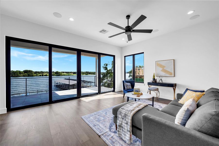 Living room with a water view, wood finished floors, recessed lighting, and ceiling fan