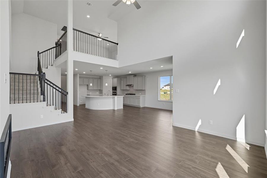 Unfurnished living room featuring dark wood-style flooring, ceiling fan, recessed lighting, and a high ceiling Unfurnished living room featuring dark wood-style flooring, ceiling fan, recessed lighting, and a high ceiling
