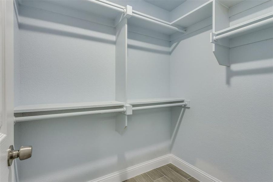 Walk in closet with wood-type flooring