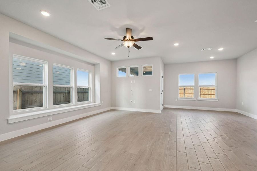 Spare room featuring light wood-style flooring, a ceiling fan, plenty of natural light, and recessed lighting