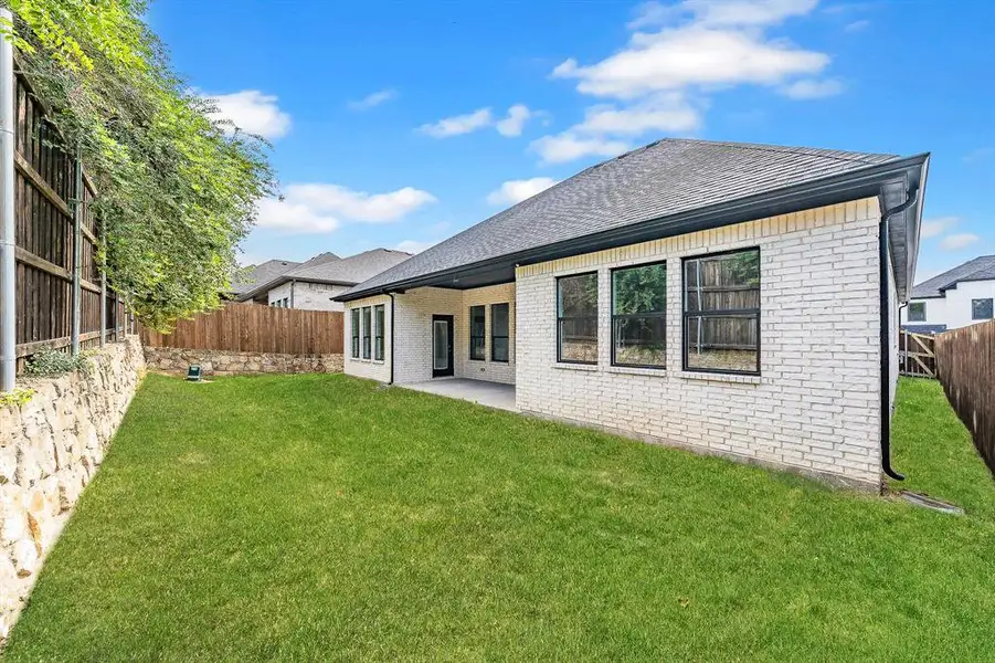 Back of property with brick siding, a fenced backyard, a patio area, and a shingled roof