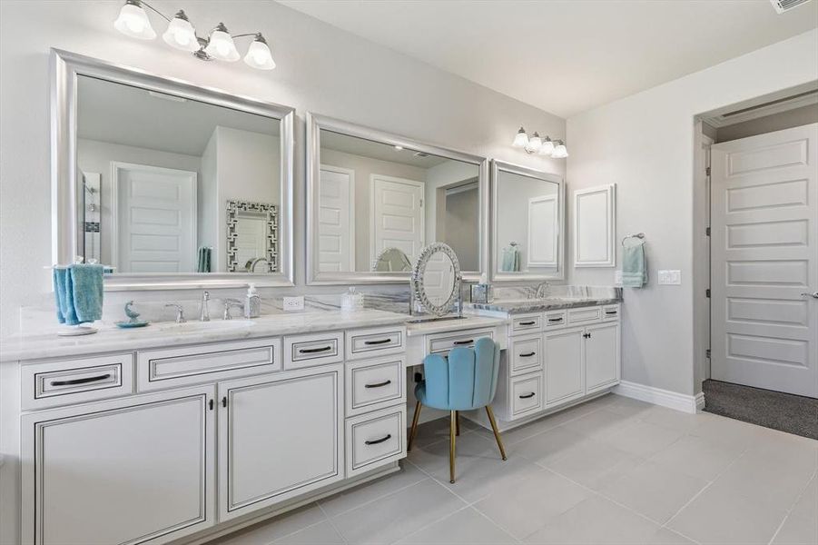 Spacious bathroom featuring dual vanities with white cabinetry, integrated sinks, and polished countertops