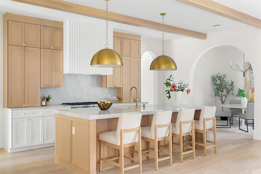 Kitchen featuring light hardwood / wood-style flooring, a kitchen island with sink, sink, and hanging light fixtures