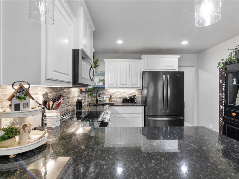 Kitchen featuring tasteful backsplash, white cabinets, appliances with stainless steel finishes, and a sink