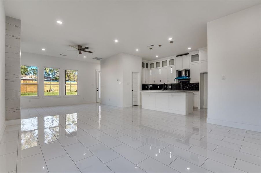 Kitchen with open floor plan, white cabinetry, recessed lighting, glass insert cabinets, and a kitchen island with sink