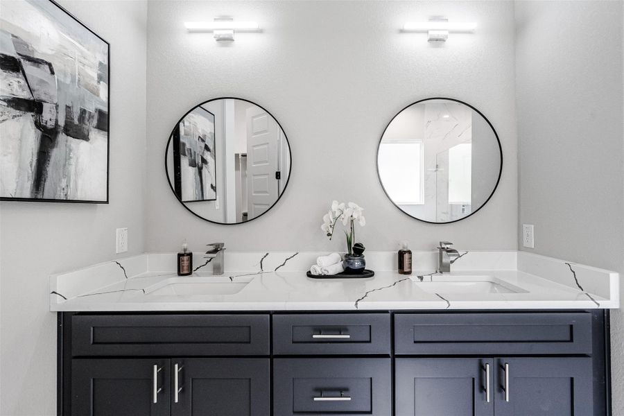 A well-appointed primary bathroom vanity features dual sinks set in sleek countertops, flanked by two circular mirrors. A well-appointed primary bathroom vanity features dual sinks set in sleek countertops, flanked by two circular mirrors.