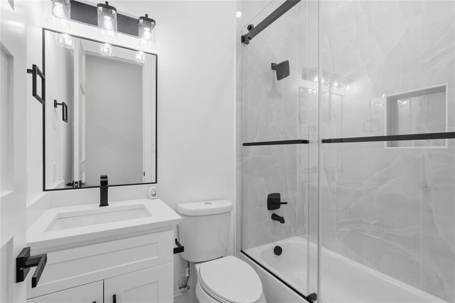 Bathroom featuring vanity and bath / shower combo with glass door