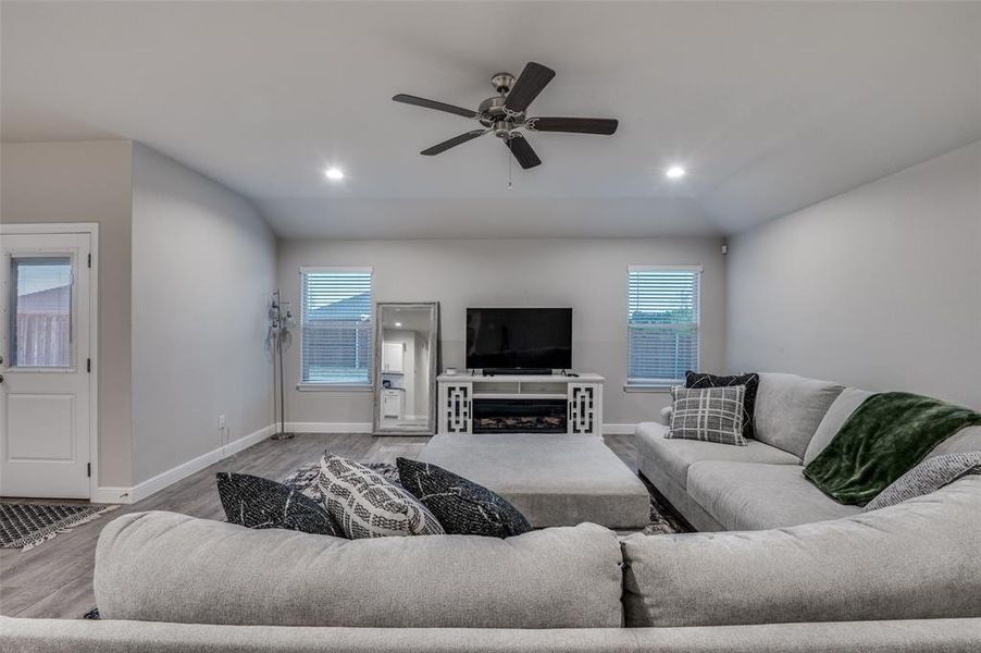 Living room with wood finished floors, ceiling fan, vaulted ceiling, and recessed lighting