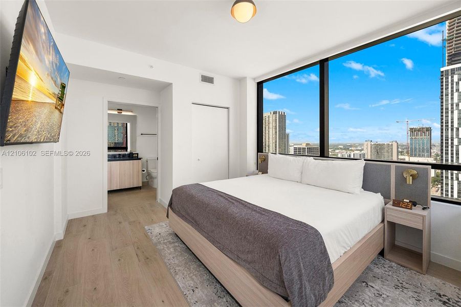Floor-to-ceiling windows with urban skyline exposure, wood-finish flooring, and minimalist interior finishes