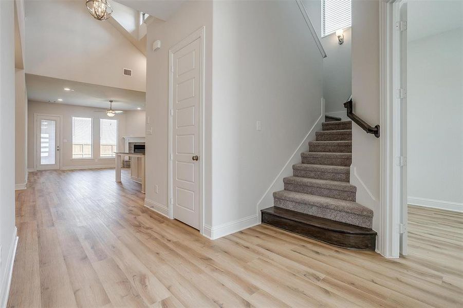 Stairs with light hardwood / wood-style floors, a towering ceiling, and ceiling fan