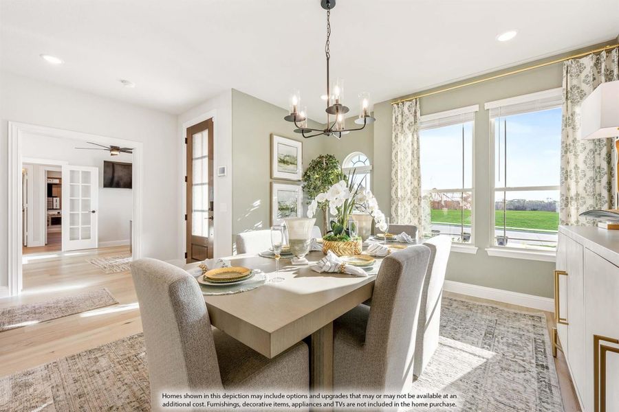 Dining room with wood table, upholstered chairs, chandelier, and large windows with garden views