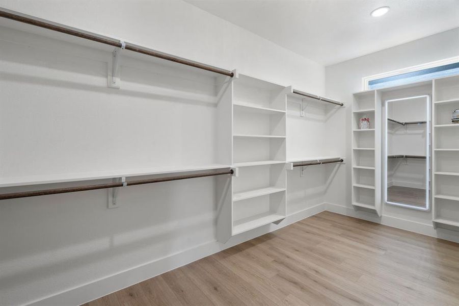 Walk in closet with light wood-style flooring Walk in closet with light wood-style flooring