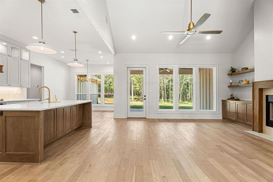 Kitchen with glass insert cabinets, brown cabinets, light wood-type flooring, healthy amount of natural light, and vaulted ceiling