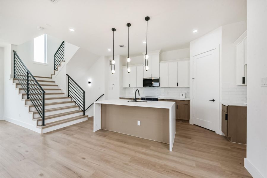 The kitchen features an island with a waterfall countertop, modern finishes, and soft wood cabinets.