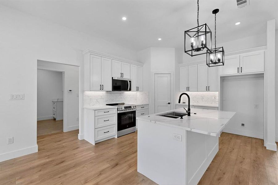 Kitchen featuring tasteful backsplash, stainless steel appliances, white cabinets, light stone counters, and recessed lighting