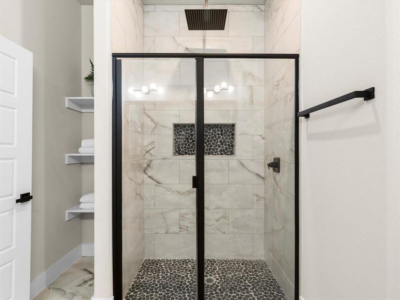 Bathroom with marble finish floors and a shower stall