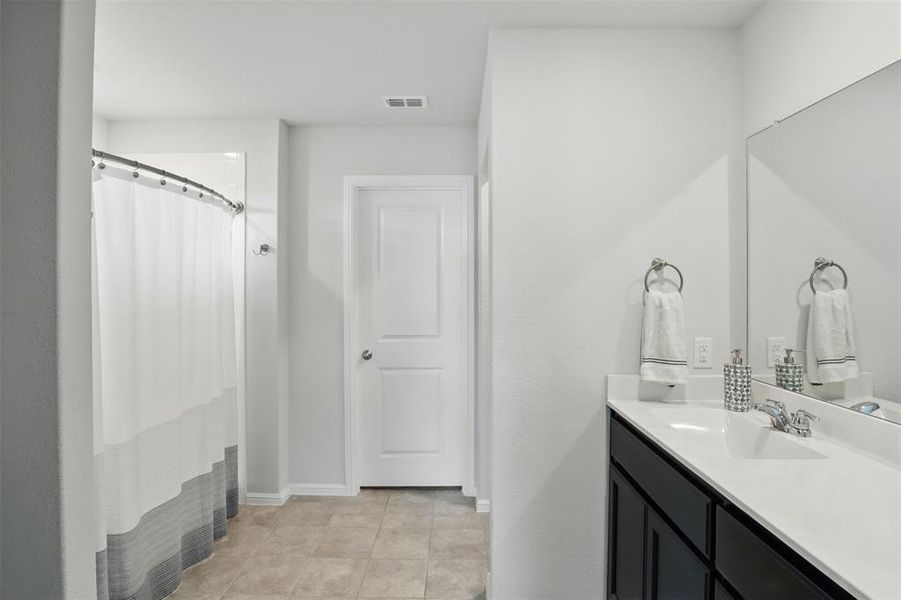 Bathroom with vanity, a shower with curtain, tile patterned flooring, baseboards, and visible vents