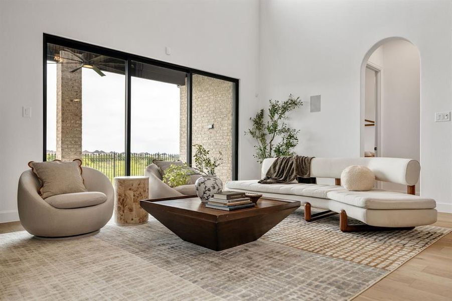Living room featuring light wood-style flooring and a high ceiling Living room featuring light wood-style flooring and a high ceiling