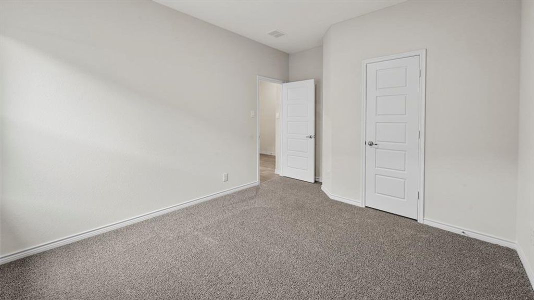 Neutral-toned room featuring light gray walls, plush gray carpeting, and white baseboards