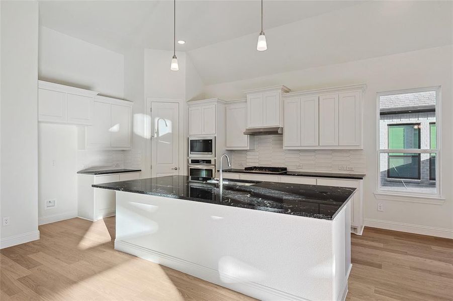 Kitchen featuring light hardwood / wood-style floors, a kitchen island with sink, stainless steel appliances, sink, and white cabinets