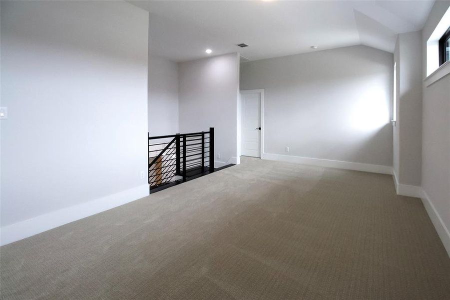 Carpeted spare room with vaulted ceiling