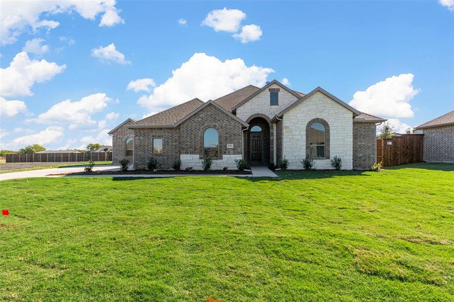 French country inspired facade featuring a front lawn