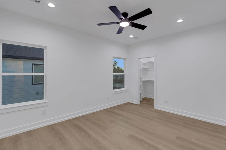 Spacious secondary bedroom with recessed lighting, ceiling fan, and direct access to a walk-in closet. Spacious secondary bedroom with recessed lighting, ceiling fan, and direct access to a walk-in closet.