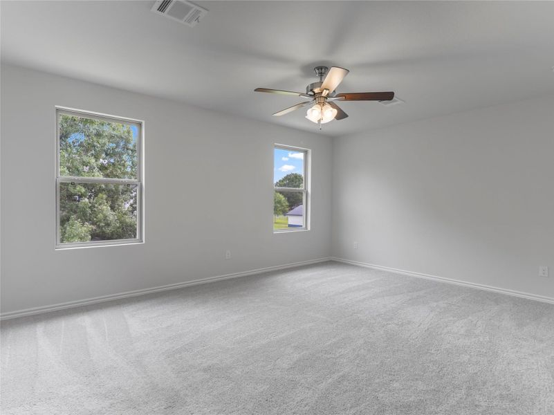 Spacious master bedroom with plush carpeting and a stylish ceiling fan for comfort and elegance. Spacious master bedroom with plush carpeting and a stylish ceiling fan for comfort and elegance.