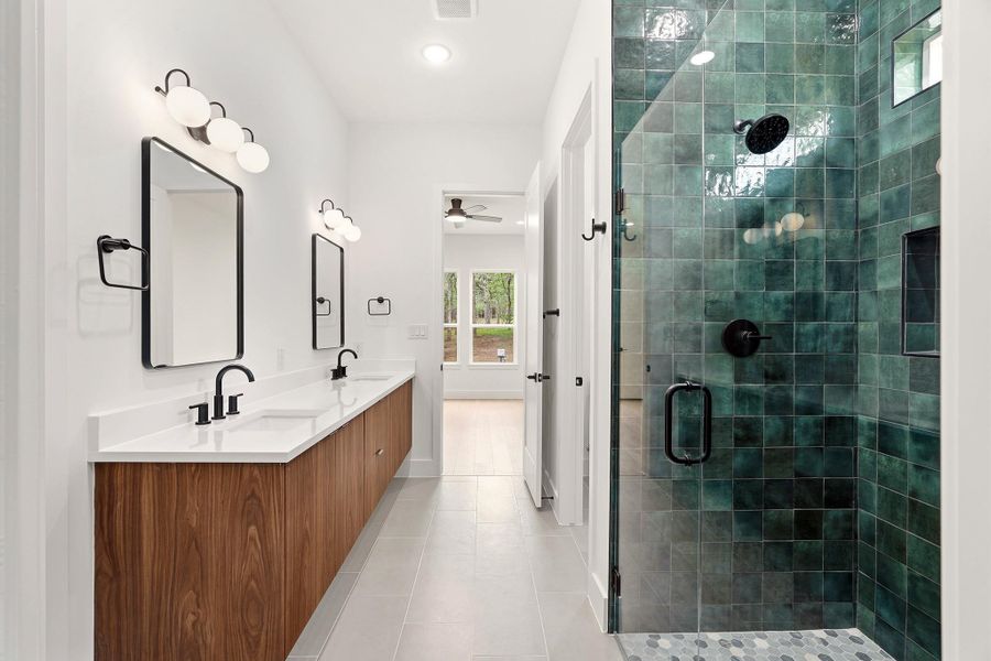 Full bath with double vanity, a stall shower, light tile patterned floors, and ceiling fan