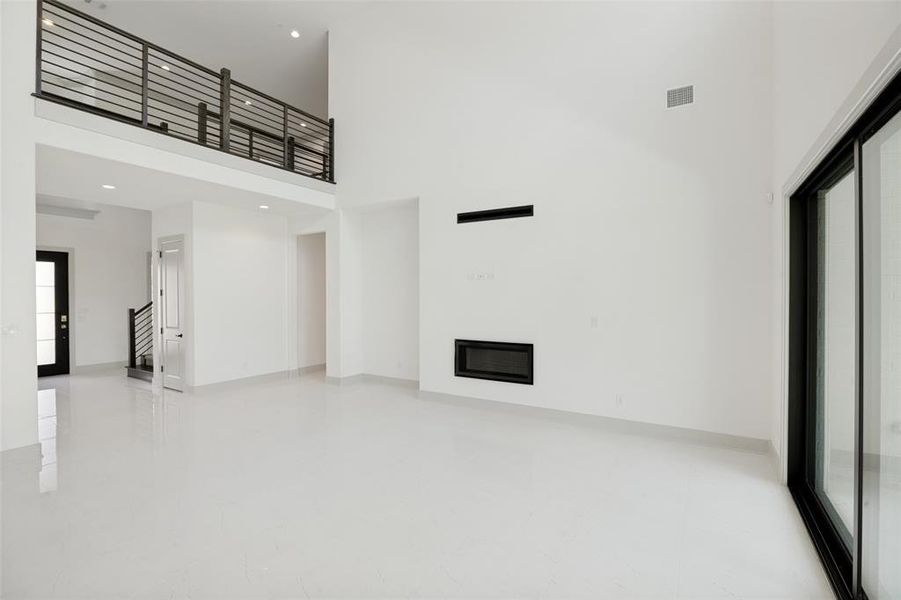 Spacious interior featuring high ceilings, white tile flooring, and a modern built-in fireplace Spacious interior featuring high ceilings, white tile flooring, and a modern built-in fireplace