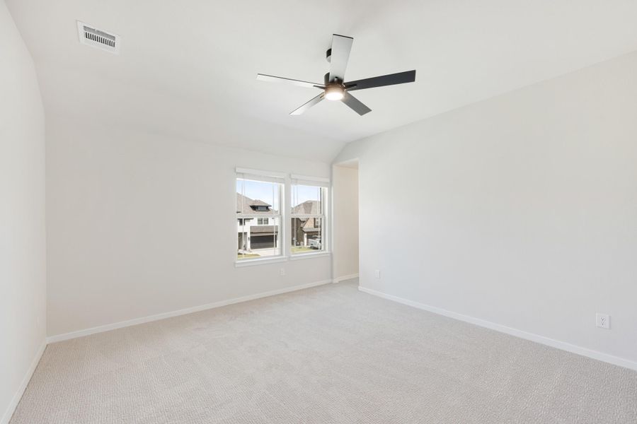 Empty bedroom with carpet flooring, vaulted ceiling, ceiling fan, and double window