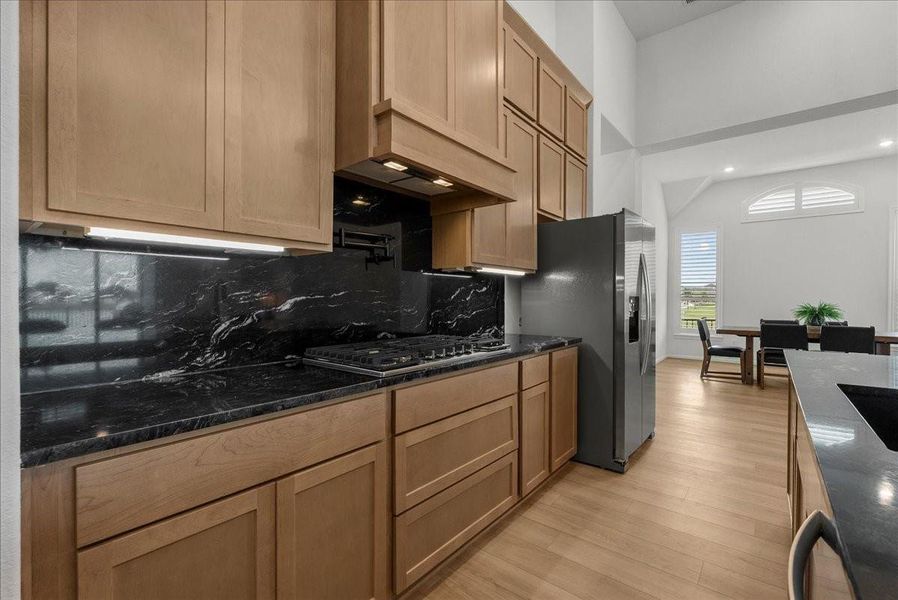 Chef’s kitchen overlooks the spacious living area and boasts double ovens, pot filler, granite countertops, designer backsplash, upgraded cabinetry, stainless steel appliances, stylish finishes, and oversized island seating.