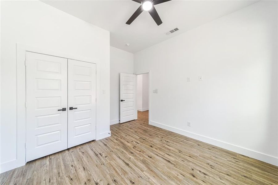 Bedroom with light wood finished floors, a closet, and ceiling fan