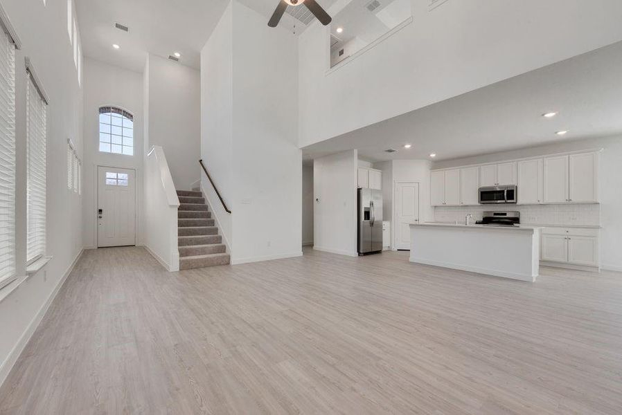 Unfurnished living room featuring stairs, recessed lighting, a high ceiling, light wood-style floors, and ceiling fan Unfurnished living room featuring stairs, recessed lighting, a high ceiling, light wood-style floors, and ceiling fan