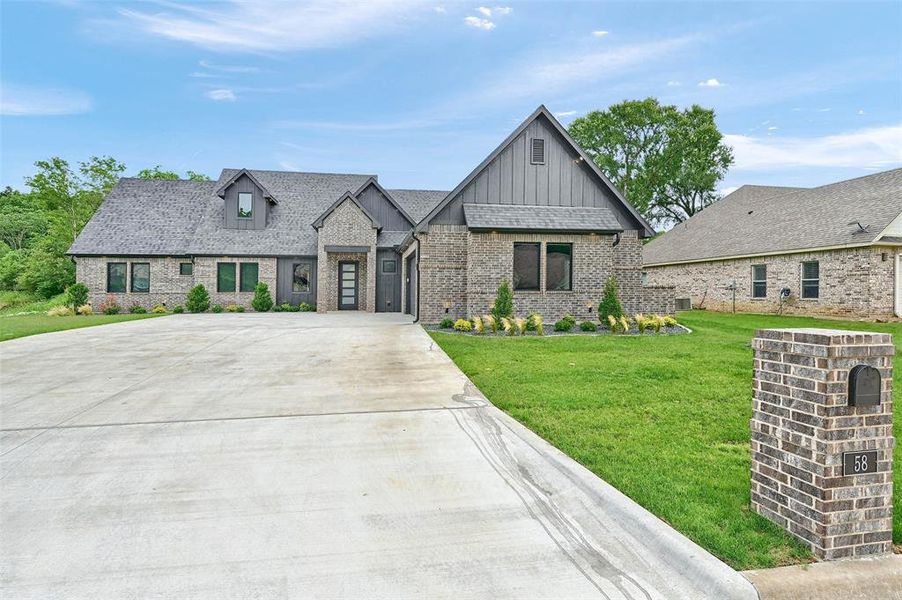 View of front of house featuring board and batten siding, brick siding, concrete driveway, and a front lawn View of front of house featuring board and batten siding, brick siding, concrete driveway, and a front lawn