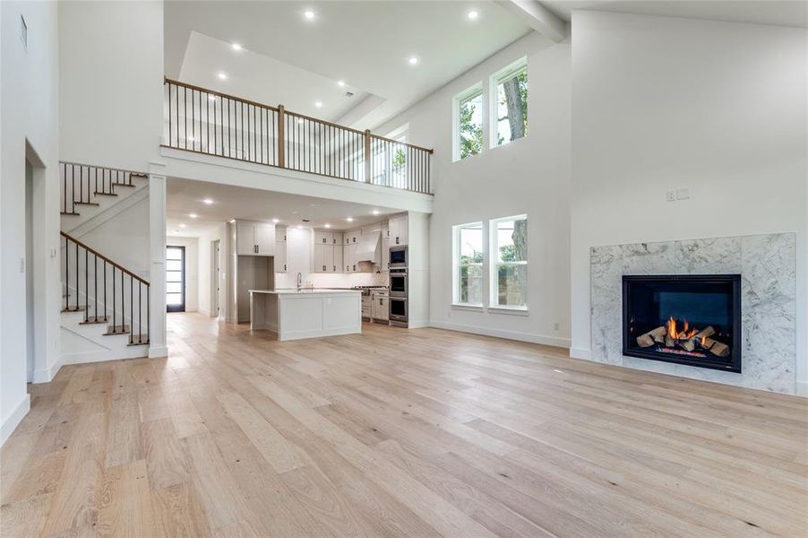 Large Open concept dining and living room featuring plenty of natural light, light wood-type flooring, a premium fireplace, beamed ceiling, and recessed lighting