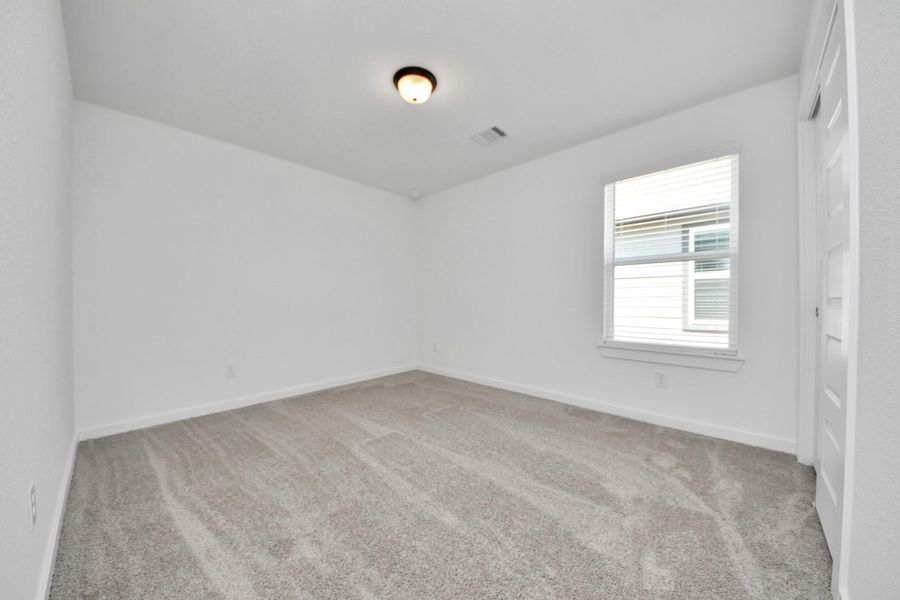 Secondary bedroom features plush carpeting, large windows that let in plenty of natural light, bright paint, and spacious closets.