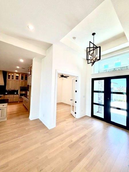 Elegant entrance foyer featuring a contemporary chandelier and durable hardwood flooring. Elegant entrance foyer featuring a contemporary chandelier and durable hardwood flooring.